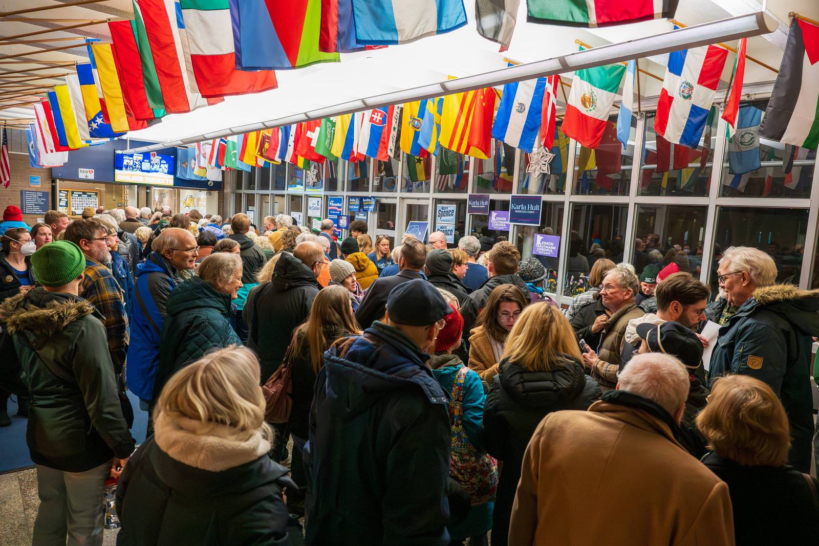 A crowded indoor market beneath rows of colorful flags.