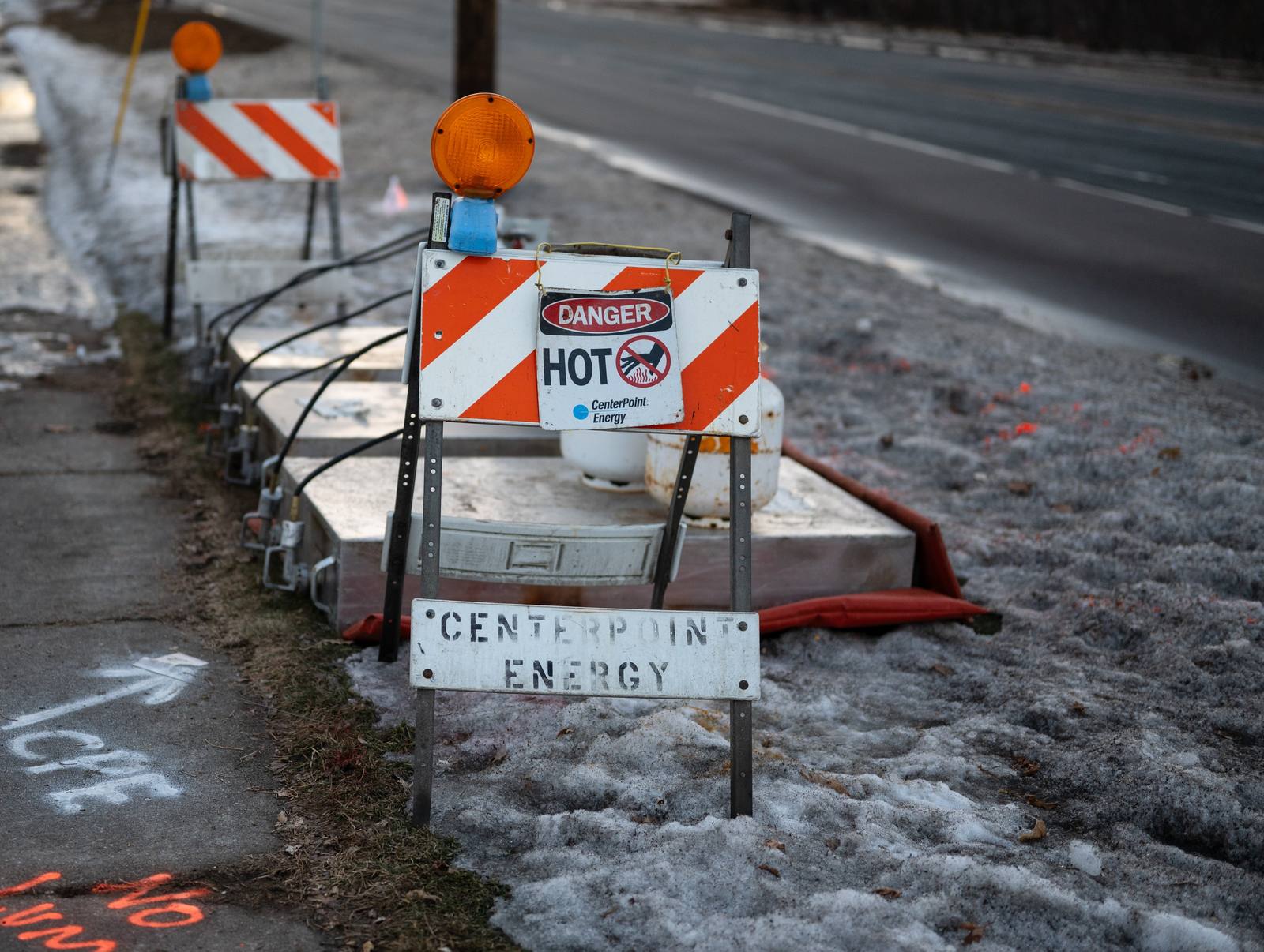 A roadside construction sign standing beside a winter curb.