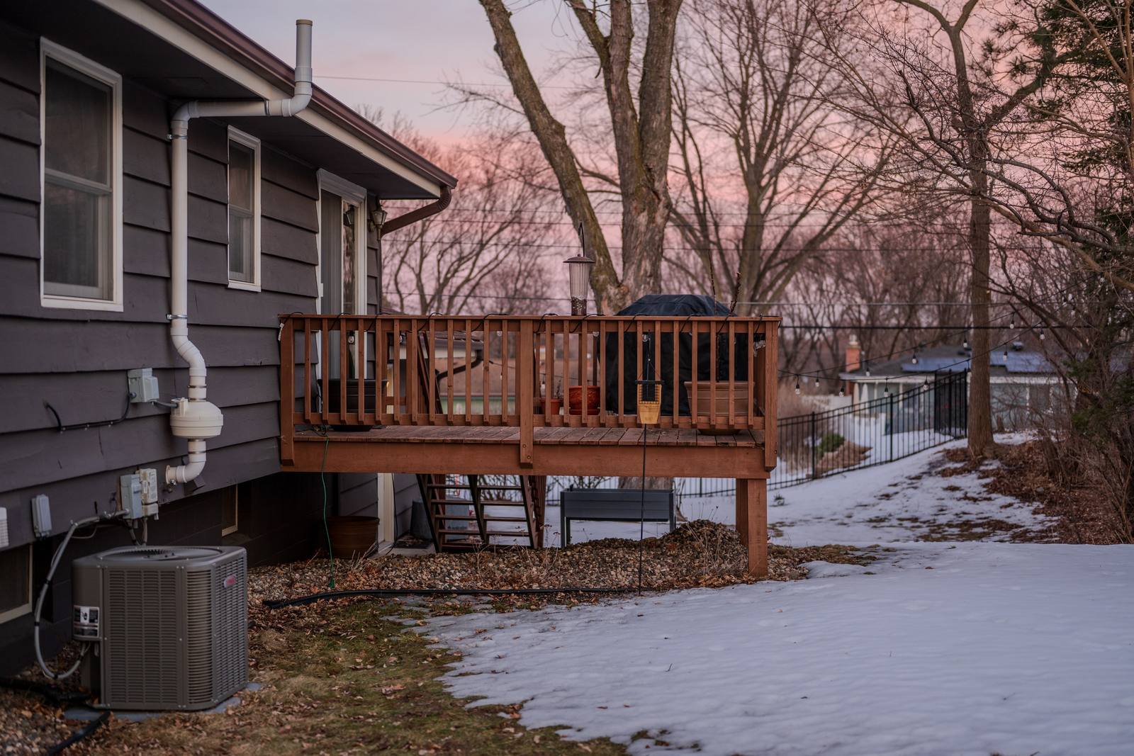 A wooden deck on a house overlooking a snow-covered yard.